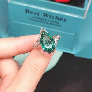 Close-up of a pear-cut Paraiba tourmaline ring with pavé diamonds in a blue gift box