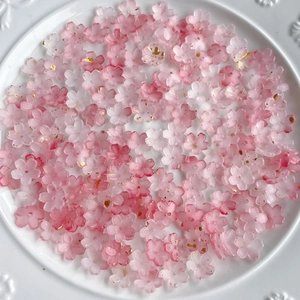 Detailed macro view of pink gradient resin cherry blossom beads with gold glitter accents