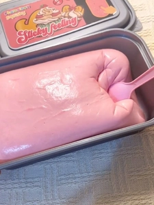 Pink slow rising squishy toy in a grey box with a small spoon for stress relief