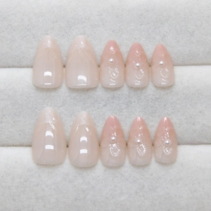 Faux ongles amande courts, dégradé nude avec perles et lignes en relief élégantes