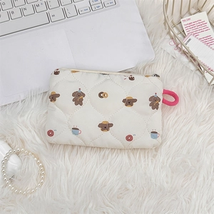 Detailed view of quilted makeup bag with teddy bear prints on a white plush background