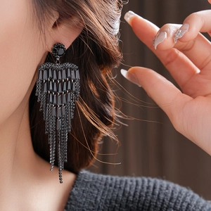 Macro detail of luxury long tassel earrings with sparkling black crystals and rhinestones