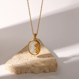 Detail of gold oval pendant with mother of pearl and sun motif on a minimalist stone base