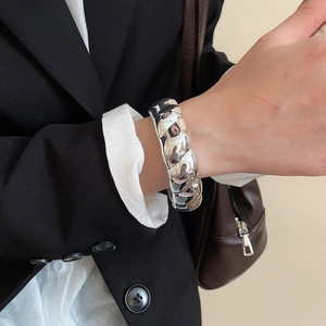Close-up of a polished silver croissant bangle shown on a model's wrist in a workplace setting