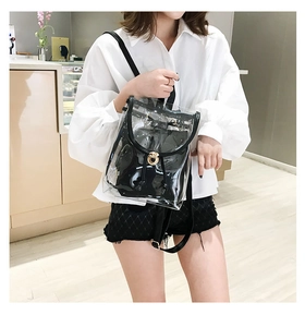 Detail of transparent PVC backpack featuring black leather trim and golden heart twist lock