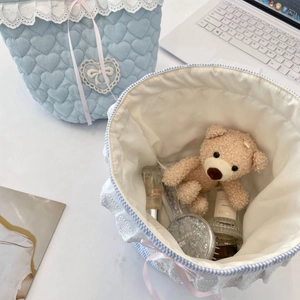 Detail of light blue quilted fabric basket with white lace trim and pink ribbon decoration