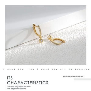 Detail of gold U-shaped brass earrings featuring micro-pave cubic zirconia stones