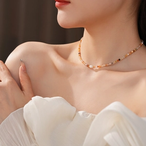 Detail of freshwater pearl necklace with colorful natural stone beads on a collarbone