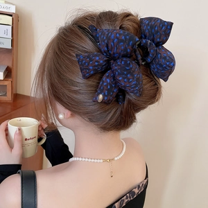 Detail of leopard print bow hair claw clip with gold metal JOY logo on elegant updo