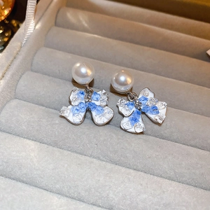 Detail of silver bow earrings with faux pearls and blue crushed stone inlay on velvet