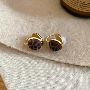 Detail of leopard print faux fur earrings with gold metal frame and white pearls