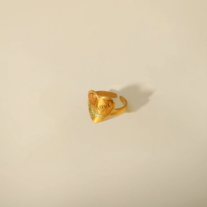 Detailed view of golden heart ring with floral engraving and LOVE inscription