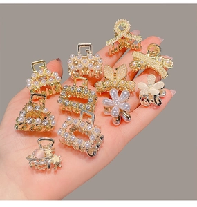 Mini alloy hair claws with rhinestones and pearls shown in palm for size scale