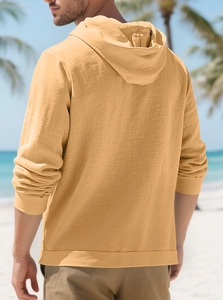 Detail view of mustard yellow linen shirt with hood and textured fabric from the back