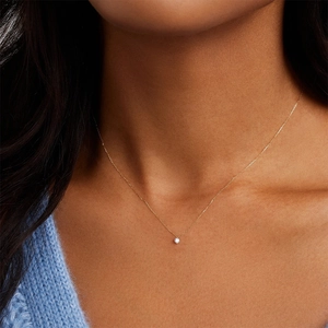 Close-up of a minimalist gold sterling silver necklace with a single zircon pendant for women