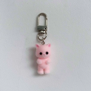 Close-up of pink flocked cat charm with silver lobster clasp on white textured background