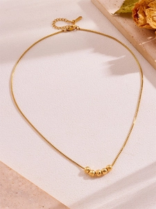 Detailed close-up of a gold titanium necklace featuring five matte beads and S.STEEL clasp