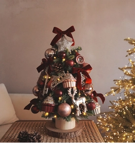 Mini Christmas tree with LED lights and red bows on a wooden base for desk decor