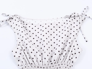 Detailed view of white polka dot sleeveless top with adjustable tie straps and smocked waist