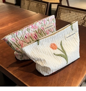 Close-up of canvas makeup bags featuring elegant floral tulip embroidery on a wooden table