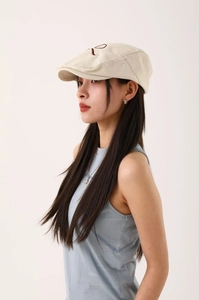Détail de la casquette gavroche beige avec broderie de la lettre R marron foncé