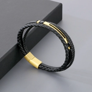 Detail of multi-layer black leather bracelet with gold magnetic clasp and metal accents