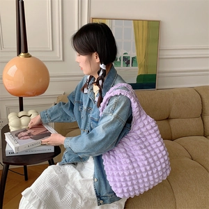 Close-up of a purple bubble textured shoulder bag styled in a cozy indoor lifestyle setting