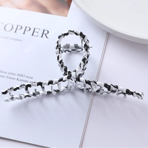 Macro shot of large black and white twisted hair claw clip with elegant wavy edges