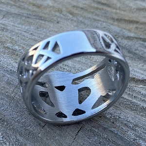 Gros plan d'une bague large argentée avec motif évidé celtique et finition en métal brossé