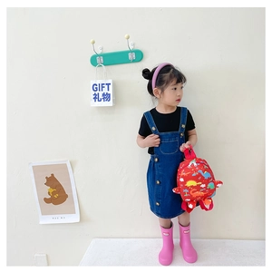 Kids red backpack with colorful dinosaur patterns shown with casual denim outfit and boots