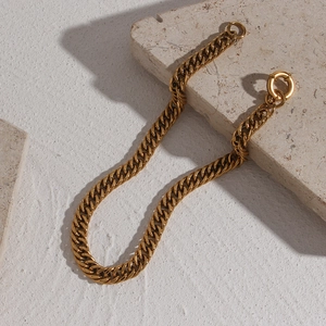Detailed close-up of a high-polish 18K gold plated Cuban link chain with a round spring clasp