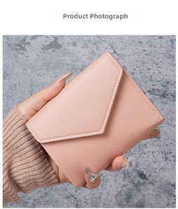Detailed view of a pink envelope wallet in cross-grain faux leather held by hand