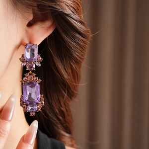 Close-up of vintage geometric square earrings with purple crystal in golden frame