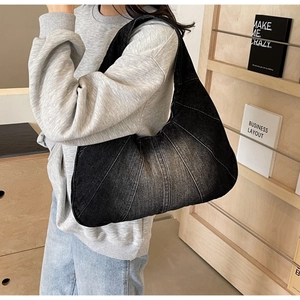 Détail du sac à bandoulière en denim noir délavé avec des coutures géométriques