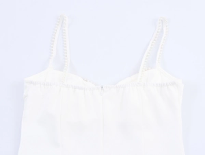 Detail of elegant white dress featuring pearl beaded straps and a hidden back zipper