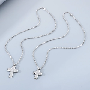 Detail of silver stainless steel cross pendant necklace featuring inlaid cubic zirconia crystals