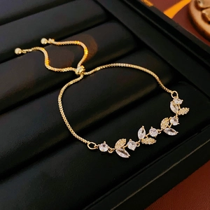 Dettaglio del bracciale con foglie di zircone placcato oro in una scatola di lusso