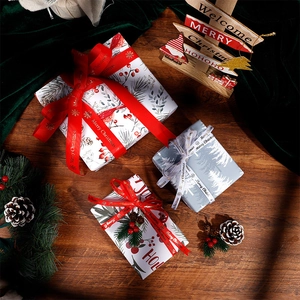 Christmas gift wrapping paper set with festive ribbons and pine needles on wood