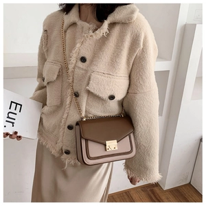 Detail of a brown and beige patchwork crossbody bag with a fine gold chain strap