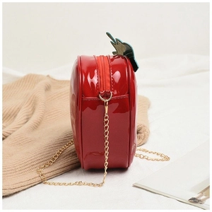 Detail view of red strawberry shaped crossbody bag with gold chain strap and glossy finish
