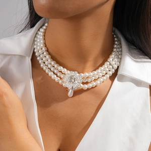 Close-up of triple-layer pearl necklace with floral rhinestone clasp and teardrop pendant