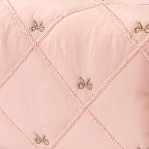 Macro detail of pink quilted fabric with elegant gold bow embroidery and stitching