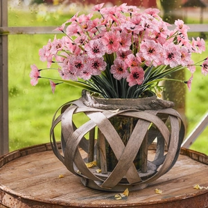 Close-up of artificial pink violets in a woven wood vase against a natural window view
