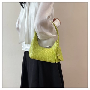 Detail of green woven shoulder bag with matching mini pouch charm shown on a model