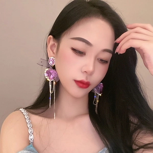 Detail of purple crystal heart earrings with long tassel chain and ribbon on model