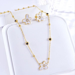 Detailed close-up of a white flower necklace and earrings set with gold chain and pearls