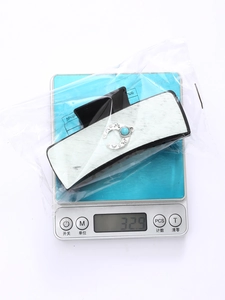 Detail showing western retro leather hair claw with turquoise on a digital weight scale