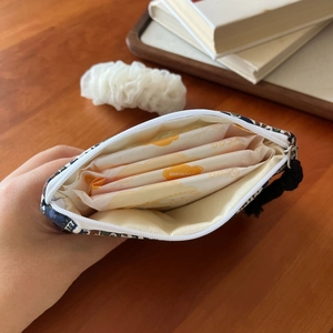 Linen pouch for feminine hygiene products shown on a rustic wooden desk with accessories
