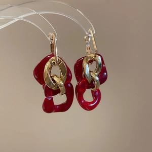 Macro view of vintage gold chain earrings with deep red acrylic links and ear hooks