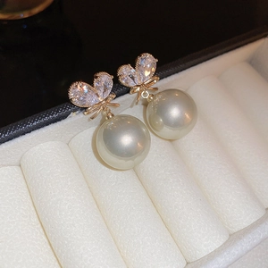 Detailed close-up of gold-plated bow earrings with inlaid crystals and large white pearls